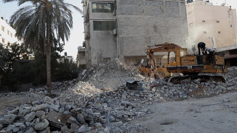 Pekerja memindahkan puing-puing bangunan yang hancur akibat serangan udara Israel, di Kota Gaza, Selasa, (15/6/2021). (AP/Tsafrir Abayov)