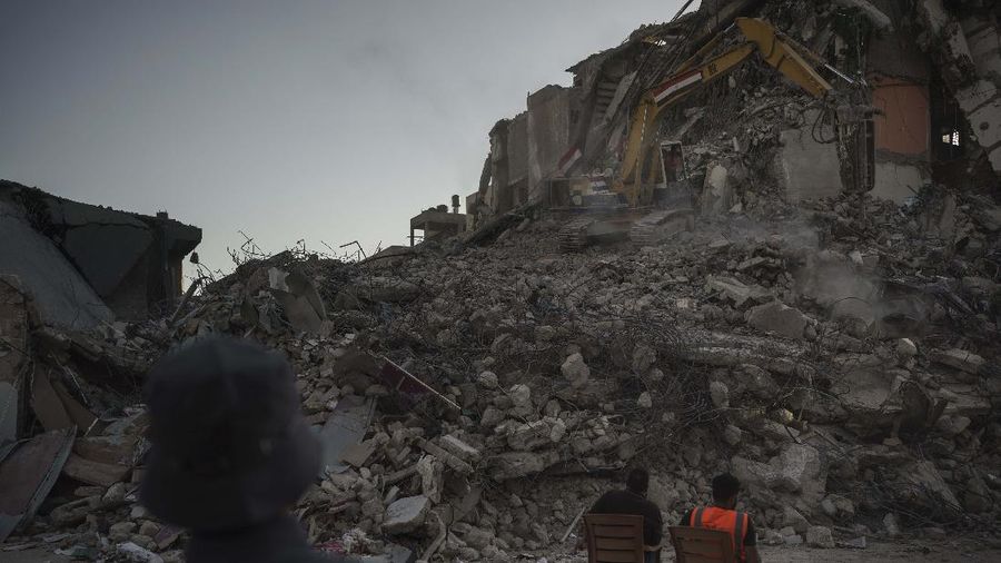 Pekerja memindahkan puing-puing bangunan yang hancur akibat serangan udara Israel, di Kota Gaza, Selasa, (15/6/2021). (AP/Tsafrir Abayov)