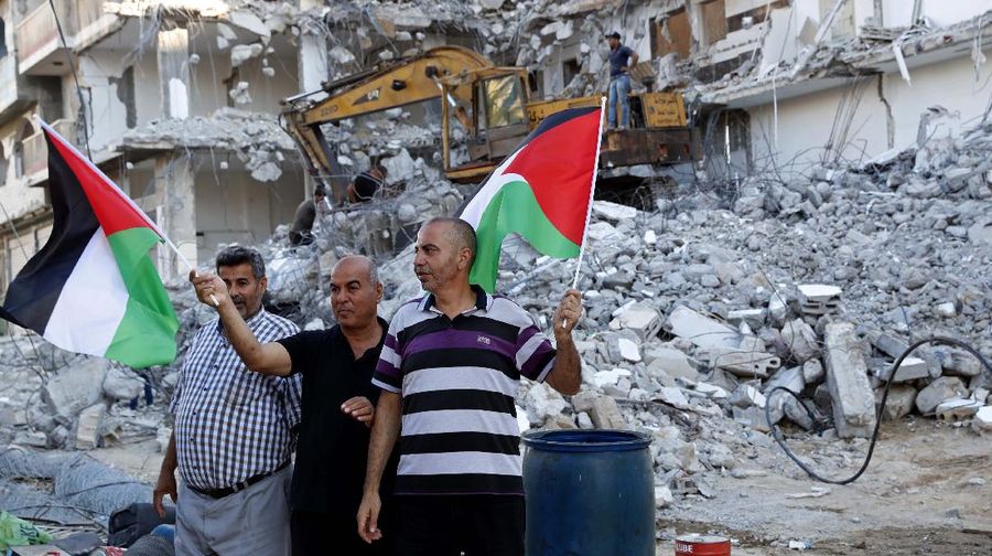 Pekerja memindahkan puing-puing bangunan yang hancur akibat serangan udara Israel, di Kota Gaza, Selasa, (15/6/2021). (AP/Tsafrir Abayov)