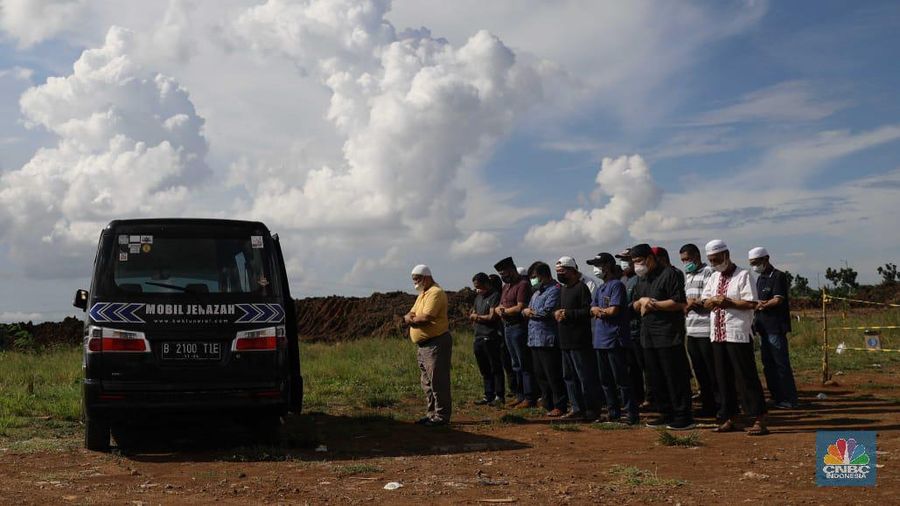 Warga melakukan salat jenazah di dekat mobil ambulans berisi jenazah yang akan dimakamkan dengan protokol COVID-19 di TPU Rorotan, Cilincing, Jakarta Utara, Selasa (15/6/21). Satgas penanganan COVID-19 melaporkan kasus konfirmasi positif hingga Selasa (15/6/2021) bertambah 8.161 orang sehingga totalnya menjadi 1.927.708 kasus, sementara itu kasus meninggal akibat COVID-19 bertambah 164 jiwa sehingga totalnya telah menembus 53.280 jiwa. (վ/ Muhammad Sabki)