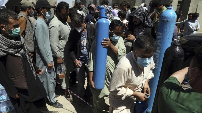 A woman carries an oxygen cylinder from a privately owned oxygen factory, in Kabul, Afghanistan, Saturday, June 19, 2021. Health officials say Afghanistan is fast running out of oxygen as a deadly third surge of COVID worsen. (AP Photo/Rahmat Gul)