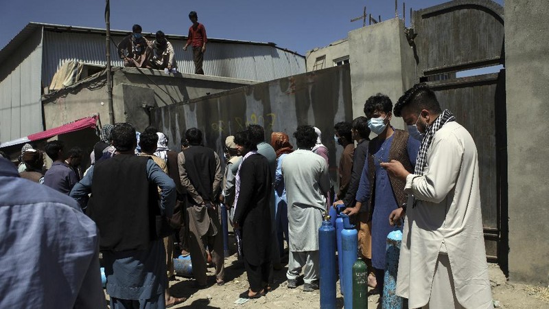 A woman carries an oxygen cylinder from a privately owned oxygen factory, in Kabul, Afghanistan, Saturday, June 19, 2021. Health officials say Afghanistan is fast running out of oxygen as a deadly third surge of COVID worsen. (AP Photo/Rahmat Gul)