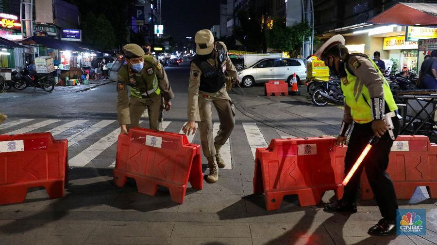 Petugas Kepolisian dan Satpol PP menutup jalan saat penerapan pembatasan mobilitas masyarakat di kawasan kuliner Jalan Sabang, Jakarta, Senin (21/6/2021). (CNBC Indonesia/ Andrean Kristianto)