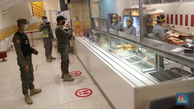 Petugas Satpol PP memberikan himbauan kepada pekerja restoran mengenai jalm pemberlakuan penerapan pembatasan mobilitas masyarakat di kawasan kuliner Jalan Sabang, Jakarta, Senin (21/6/2021). (CNBC Indonesia/ Andrean Kristianto)