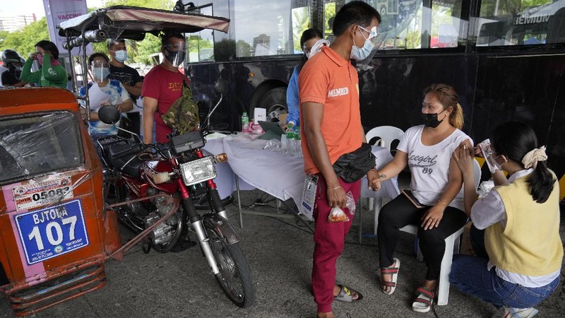 A health worker inoculates a woman with China's Sinovac COVID-19 vaccine at a temporary vaccination center in Manila, Philippines, Tuesday, June 22, 2021. The Philippine president has threatened to order the arrest of Filipinos who refuse COVID-19 vaccination and told them to leave the country for hard-hit countries like India and the United States if they would not cooperate with massive efforts to end the pandemic. (AP Photo/Aaron Favila)
