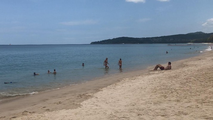 In this March 26, 2020, photo, tourists swim on a beach, Phuket, Thailand. Tourists across Asia are finding their dream vacations have turned into travel nightmares as airlines cancel flights and countries close their borders in the fight against the coronavirus pandemic. (AP Photo/Penny Wang)