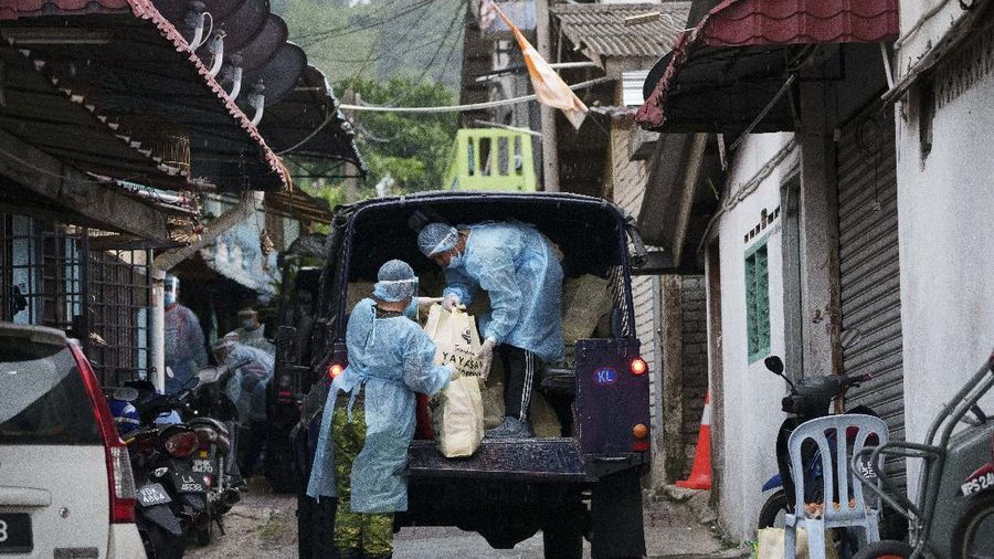 A resident wearing face mask sit outside his house next to barbwire at Segambut Dalam area placed under the enhanced movement control order (EMCO) due to drastic increase in the number of COVID-19 cases recorded over the past 10 days in Kuala Lumpur, Malaysia, Sunday, June 27, 2021. Malaysia's leader says a one-month near total lockdown that is due to end Monday will be extended further as coronavirus infections remain high. (AP Photo/Vincent Thian)