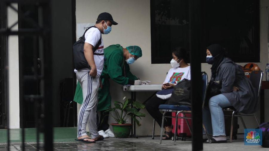Petugas menggunakan Alat Pelindung Diri (APD) mendata pasien untuk masuk ke dalam bus sekolah di Puskesmas Kecamatan Setiabudi, Jakarta, Selasa (29/6/2021). Puskesmas Kecamatan Setiabudi  pada hari ini menjemput pasien Covid-19 sebanyak 50 orang. Puluhan pasien tersebut dibawa ke Wisma Atlet. Data Covid-19 hingga Senin (28/6/2021) mencatat total ada 2,1 juta orang positif di Indonesia. Sementara itu, total kematian sudah mencapai 57,561 orang. Pemerintah akan mengumumkan revisi aturan terkait pemberlakuan pembatasan kegiatan masyarakat (PPKM) berbasis mikro pada petang ini. Presiden Joko Widodo (Jokowi) memutuskan akan memberlakukan PPKM Darurat untuk mengatasi lonjakan kasus Covid-19. Kebijakan ini tidak lepas dari kondisi kasus positif Covid-19 harian di Indonesia sudah mencapai 20 ribuan per hari, semakin naik dibanding sebelumnya. Sementara itu jika merujuk pada data worldmeter, Indonesia berada di urutan ke 17. Adapun jumlah tes yang dilakukan terbilang minim hanya 71.051 per 1 juta penduduk. Jauh dibandingkan negara lain yang mencapai ratusan ribu per 1 juta penduduk. (CNBC Indonesia/ Muhammad Sabki)
