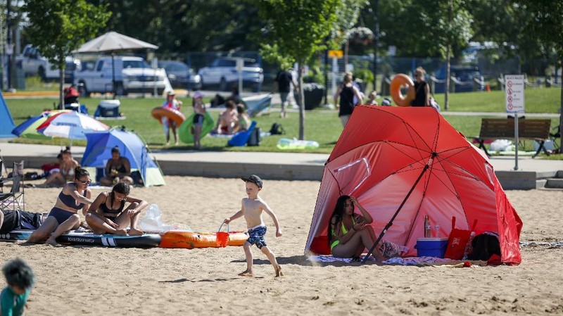 A man stands under a water feature trying to beat the heat at a splash park in Calgary, Alberta, Wednesday, June 30, 2021. Environment Canada warns the torrid heat wave that has settled over much of Western Canada won't lift for days. (Jeff McIntosh/The Canadian Press via AP)