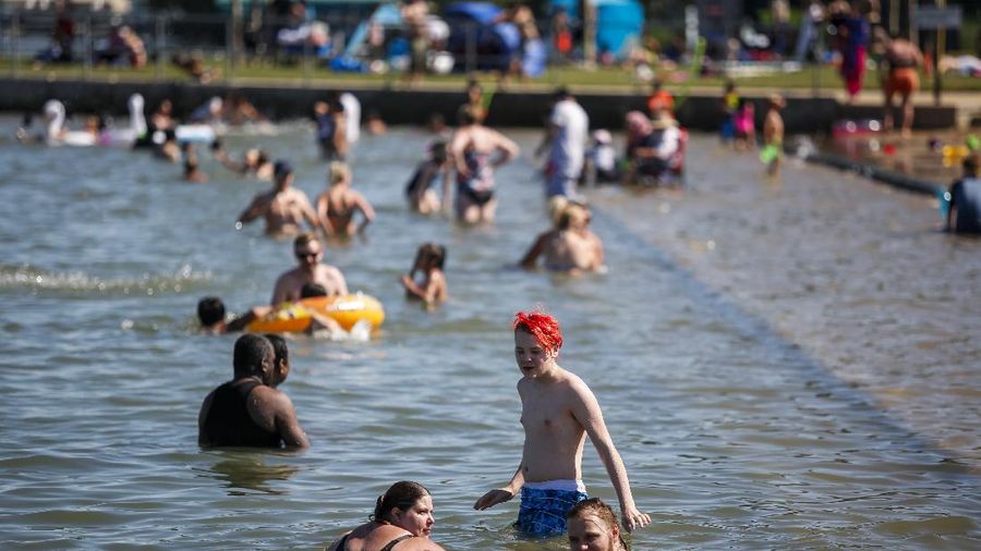 A man stands under a water feature trying to beat the heat at a splash park in Calgary, Alberta, Wednesday, June 30, 2021. Environment Canada warns the torrid heat wave that has settled over much of Western Canada won't lift for days. (Jeff McIntosh/The Canadian Press via AP)