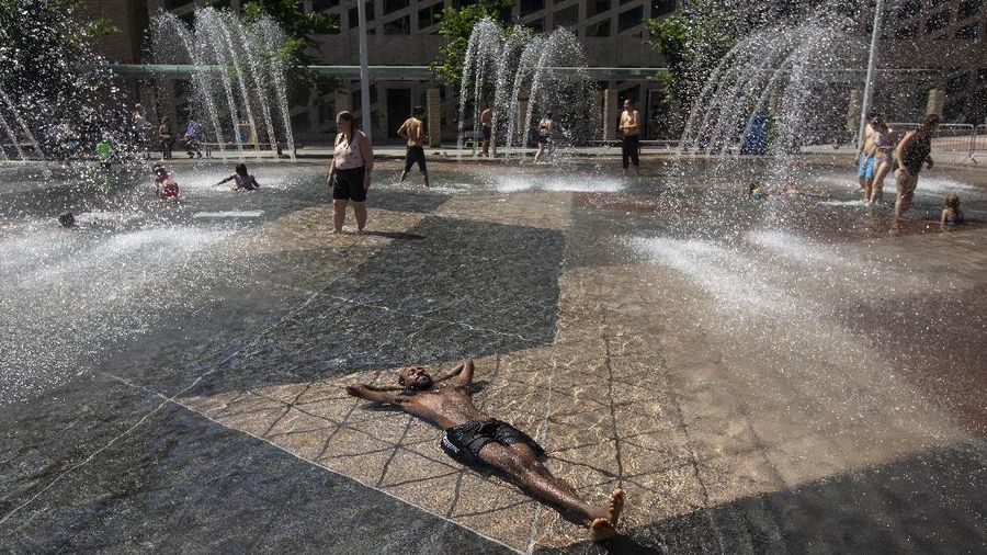 A man stands under a water feature trying to beat the heat at a splash park in Calgary, Alberta, Wednesday, June 30, 2021. Environment Canada warns the torrid heat wave that has settled over much of Western Canada won't lift for days. (Jeff McIntosh/The Canadian Press via AP)