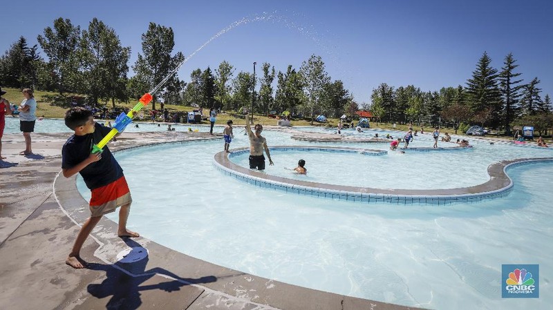 A man stands under a water feature trying to beat the heat at a splash park in Calgary, Alberta, Wednesday, June 30, 2021. Environment Canada warns the torrid heat wave that has settled over much of Western Canada won't lift for days. (Jeff McIntosh/The Canadian Press via AP)
