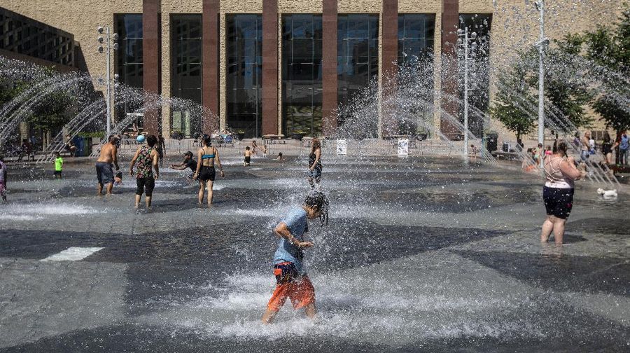 A man stands under a water feature trying to beat the heat at a splash park in Calgary, Alberta, Wednesday, June 30, 2021. Environment Canada warns the torrid heat wave that has settled over much of Western Canada won't lift for days. (Jeff McIntosh/The Canadian Press via AP)