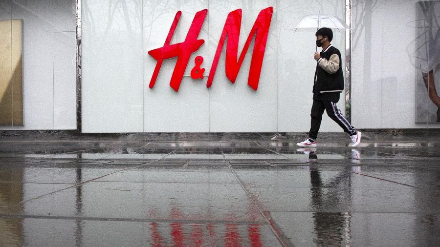 FILE - In this March 26, 2021, file photo, a man carrying an umbrella walks past an H&M clothing store at a shopping mall in Beijing. Chinese regulators on Friday, April 2, 2021, said H&M has agreed to change a “problem map” online following government criticism, adding to pressure on the Swedish retailer amid a conflict with Western governments over Chinese policies in its Xinjiang region. (AP Photo/Mark Schiefelbein, File)
