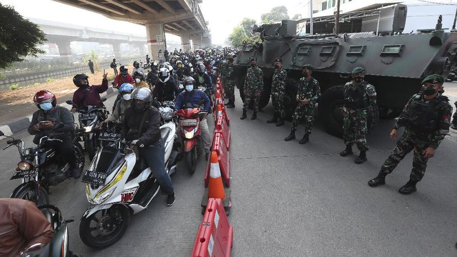 Aparat berjaga pos penyekatan PPKM Darurat di Kalimalang, Jakarta, Senin (5/7/2021). (AP/Achmad Ibrahim)