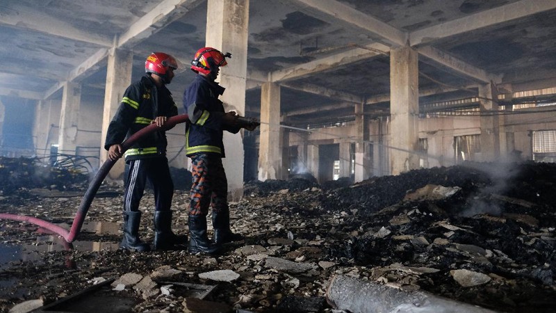 Firefighters work to douse a fire at a food and beverage factory in Rupganj, outside Dhaka, Bangladesh, Friday, July 9, 2021. At least 52 people died in a huge blaze that engulfed a food and beverage factory outside Bangladesh's capital, fire officials said Friday, in the latest industrial disaster to hit the South Asian nation. (AP Photo/Mahmud Hossain Opu)