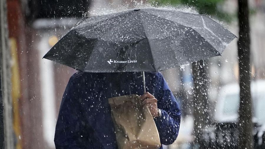 A pedestrian uses an umbrella to shield himself during a downpour from Tropical Storm Elsa, Friday, July 9, 2021, in Portland, Maine. Elsa is the earliest fifth-named storm on record, said Brian McNoldy, a hurricane researcher at the University of Miami. (AP Photo/Robert F. Bukaty)