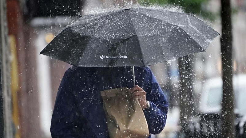 A pedestrian uses an umbrella to shield himself during a downpour from Tropical Storm Elsa, Friday, July 9, 2021, in Portland, Maine. Elsa is the earliest fifth-named storm on record, said Brian McNoldy, a hurricane researcher at the University of Miami. (AP Photo/Robert F. Bukaty)