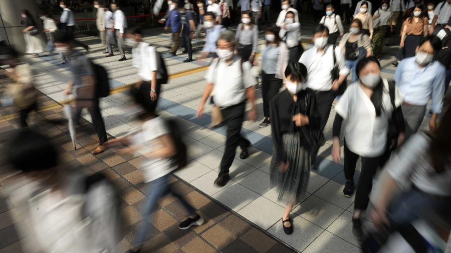 Commuters wearing face masks walk in a passageway during a rush hour at Shinagawa Station Monday, July 12, 2021, in Tokyo. Japan declared a fourth state of emergency for Tokyo from Monday until Aug. 22. (AP Photo/Eugene Hoshiko)