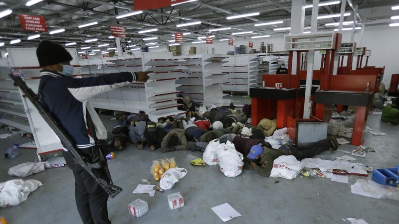 Looters run as policer officers chassis at a shopping centre in Soweto, Johannesburg, Tuesd in Johannesburg, South Africa, Tuesday, July 13, 2021. South Africa's rioting continued Tuesday with the death toll rising to 32 as police and the military struggle to quell the violence in Gauteng and KwaZulu-Natal provinces. The violence started in various parts of KwaZulu-Natal last week when Zuma began serving a 15-month sentence for contempt of court. (AP Photo/Themba Hadebe)