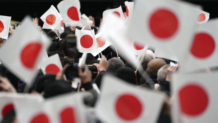 Well-wishers wave Japanese flags while waiting to see Japan's Emperor Naruhito making New Year's public appearance with his imperial families at Imperial Palace in Tokyo Thursday, Jan. 2, 2020. (AP Photo/Eugene Hoshiko)