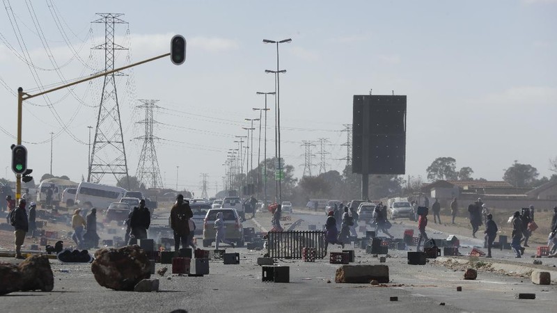 Looters run as policer officers chassis at a shopping centre in Soweto, Johannesburg, Tuesd in Johannesburg, South Africa, Tuesday, July 13, 2021. South Africa's rioting continued Tuesday with the death toll rising to 32 as police and the military struggle to quell the violence in Gauteng and KwaZulu-Natal provinces. The violence started in various parts of KwaZulu-Natal last week when Zuma began serving a 15-month sentence for contempt of court. (AP Photo/Themba Hadebe)