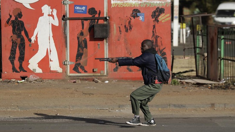 Looters run as policer officers chassis at a shopping centre in Soweto, Johannesburg, Tuesd in Johannesburg, South Africa, Tuesday, July 13, 2021. South Africa's rioting continued Tuesday with the death toll rising to 32 as police and the military struggle to quell the violence in Gauteng and KwaZulu-Natal provinces. The violence started in various parts of KwaZulu-Natal last week when Zuma began serving a 15-month sentence for contempt of court. (AP Photo/Themba Hadebe)
