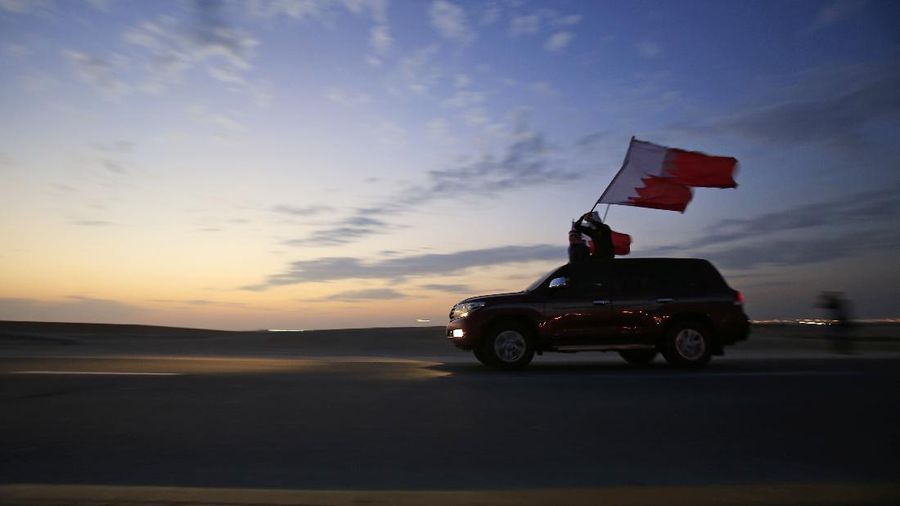 Men on top of a car wave national flags during Bahrain's National Day in Sakhir, Bahrain, Tuesday, Dec. 16, 2014. (AP Photo/Hasan Jamali)