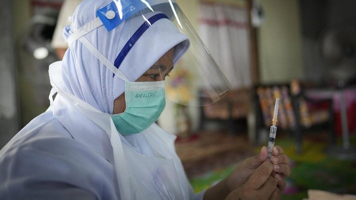 A nurse administers a Pfizer COVID-19 vaccine to an elderly man in his house in rural Sabab Bernam, central Selangor state, Malaysia, Tuesday, July 13, 2021. Medical teams are going house to house in rural villages to reach out to elderly citizens as the government seeks to ramp up its vaccination program. Despite a strict lockdown, the pandemic has worsened with more than 844,000 confirmed cases nationwide and over 6,200 deaths. (AP Photo/Vincent Thian)
