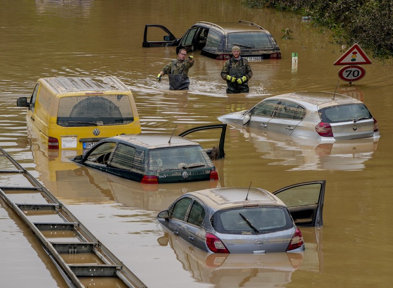 Helpers check for victims in flooded cars on a road in Erftstadt, Germany, Saturday, July 17, 2021. Due to strong rainfall,  the small Erft river went over its banks,  causing massive damage. (AP Photo/Michael Probst)