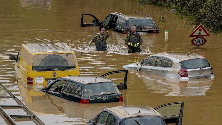 Helpers check for victims in flooded cars on a road in Erftstadt, Germany, Saturday, July 17, 2021. Due to strong rainfall,  the small Erft river went over its banks,  causing massive damage. (AP Photo/Michael Probst)