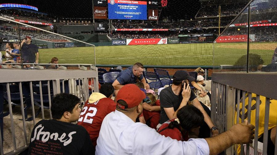 Fans jump into a camera well after hearing gunfire from outside the stadium, during a baseball game between the San Diego Padres and the Washington Nationals at Nationals Park in Washington on Saturday, July 17, 2021. (John McDonnell/The Washington Post via AP)