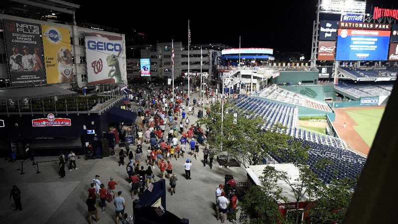 Fans jump into a camera well after hearing gunfire from outside the stadium, during a baseball game between the San Diego Padres and the Washington Nationals at Nationals Park in Washington on Saturday, July 17, 2021. (John McDonnell/The Washington Post via AP)