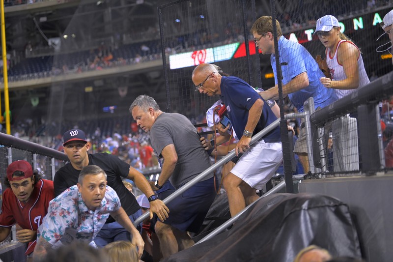 Penemabakan di Luar Stadion AS Saat Pertandingan Baseball Fans jump into a camera well after hearing gunfire from outside the stadium, during a baseball game between the San Diego Padres and the Washington Nationals at Nationals Park in Washington on Saturday, July 17, 2021. (John McDonnell/The Washington Post via AP)