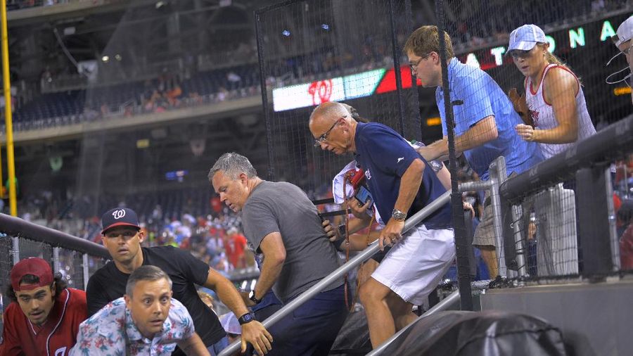 Fans jump into a camera well after hearing gunfire from outside the stadium, during a baseball game between the San Diego Padres and the Washington Nationals at Nationals Park in Washington on Saturday, July 17, 2021. (John McDonnell/The Washington Post via AP)