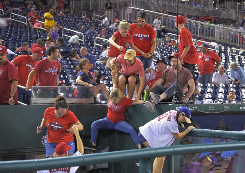 Penemabakan di Luar Stadion AS Saat Pertandingan Baseball Fans jump into a camera well after hearing gunfire from outside the stadium, during a baseball game between the San Diego Padres and the Washington Nationals at Nationals Park in Washington on Saturday, July 17, 2021. (John McDonnell/The Washington Post via AP)