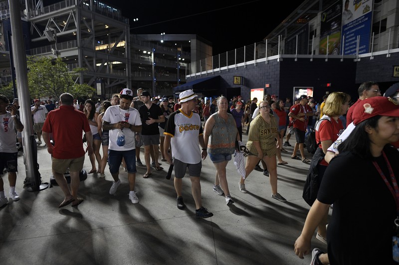 Fans jump into a camera well after hearing gunfire from outside the stadium, during a baseball game between the San Diego Padres and the Washington Nationals at Nationals Park in Washington on Saturday, July 17, 2021. (John McDonnell/The Washington Post via AP)