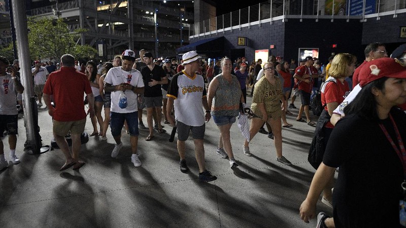 Fans jump into a camera well after hearing gunfire from outside the stadium, during a baseball game between the San Diego Padres and the Washington Nationals at Nationals Park in Washington on Saturday, July 17, 2021. (John McDonnell/The Washington Post via AP)
