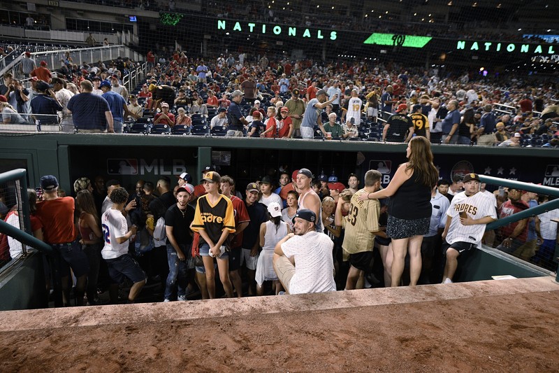 Penemabakan di Luar Stadion AS Saat Pertandingan Baseball Fans jump into a camera well after hearing gunfire from outside the stadium, during a baseball game between the San Diego Padres and the Washington Nationals at Nationals Park in Washington on Saturday, July 17, 2021. (John McDonnell/The Washington Post via AP)