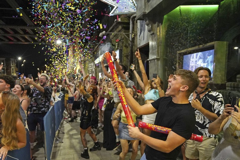 People celebrate as they queue up for entry at the Viaduct Bar in Leeds, after the final legal coronavirus restrictions were lifted in England at midnight, Monday, July 19, 2021. (Ioannis Alexopoulos/PA via AP)