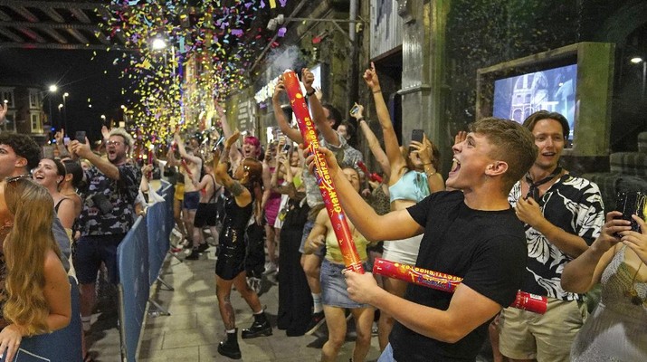 People celebrate as they queue up for entry at the Viaduct Bar in Leeds, after the final legal coronavirus restrictions were lifted in England at midnight, Monday, July 19, 2021. (Ioannis Alexopoulos/PA via AP)