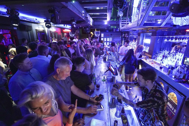 People celebrate as they queue up for entry at the Viaduct Bar in Leeds, after the final legal coronavirus restrictions were lifted in England at midnight, Monday, July 19, 2021. (Ioannis Alexopoulos/PA via AP)