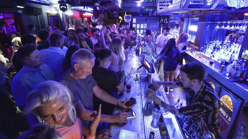 People celebrate as they queue up for entry at the Viaduct Bar in Leeds, after the final legal coronavirus restrictions were lifted in England at midnight, Monday, July 19, 2021. (Ioannis Alexopoulos/PA via AP)
