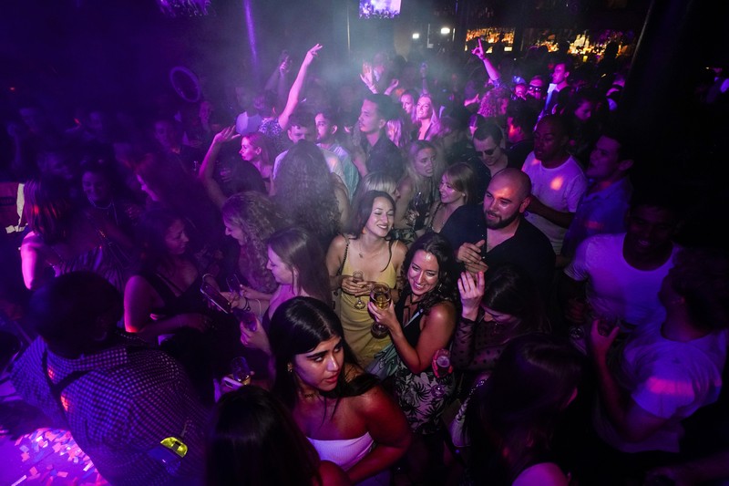 People celebrate as they queue up for entry at the Viaduct Bar in Leeds, after the final legal coronavirus restrictions were lifted in England at midnight, Monday, July 19, 2021. (Ioannis Alexopoulos/PA via AP)
