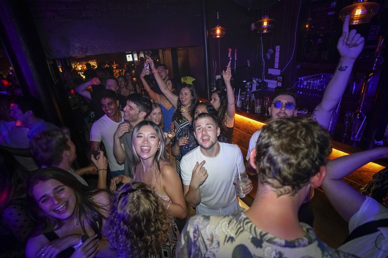 People celebrate as they queue up for entry at the Viaduct Bar in Leeds, after the final legal coronavirus restrictions were lifted in England at midnight, Monday, July 19, 2021. (Ioannis Alexopoulos/PA via AP)