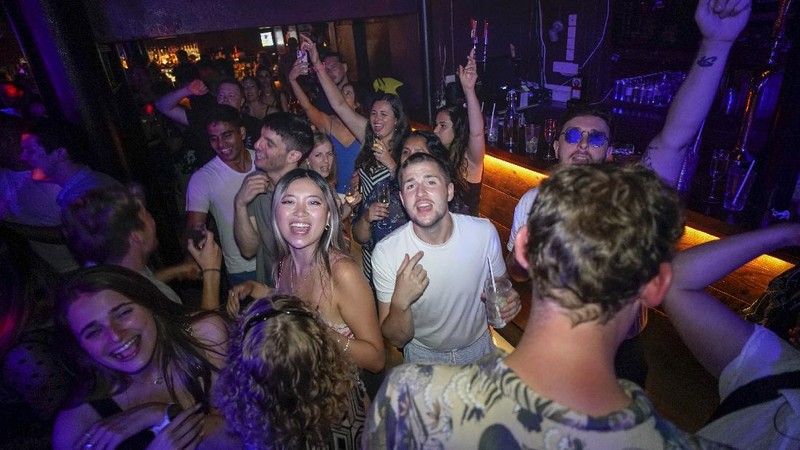 People celebrate as they queue up for entry at the Viaduct Bar in Leeds, after the final legal coronavirus restrictions were lifted in England at midnight, Monday, July 19, 2021. (Ioannis Alexopoulos/PA via AP)