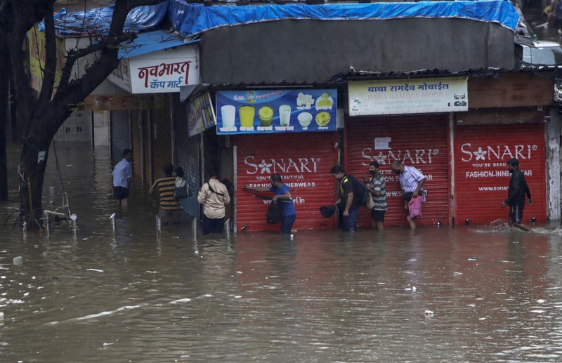 Rescuers carry a dead body of a man after a wall collapsed on several slum houses heavy monsoon rains in the Mahul area of Mumbai, India, Sunday, July 18, 2021. More than a dozen people were killed in the incident. (AP Photo/Rajanish Kakade)