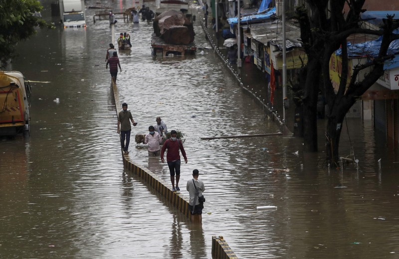 Rescuers carry a dead body of a man after a wall collapsed on several slum houses heavy monsoon rains in the Mahul area of Mumbai, India, Sunday, July 18, 2021. More than a dozen people were killed in the incident. (AP Photo/Rajanish Kakade)