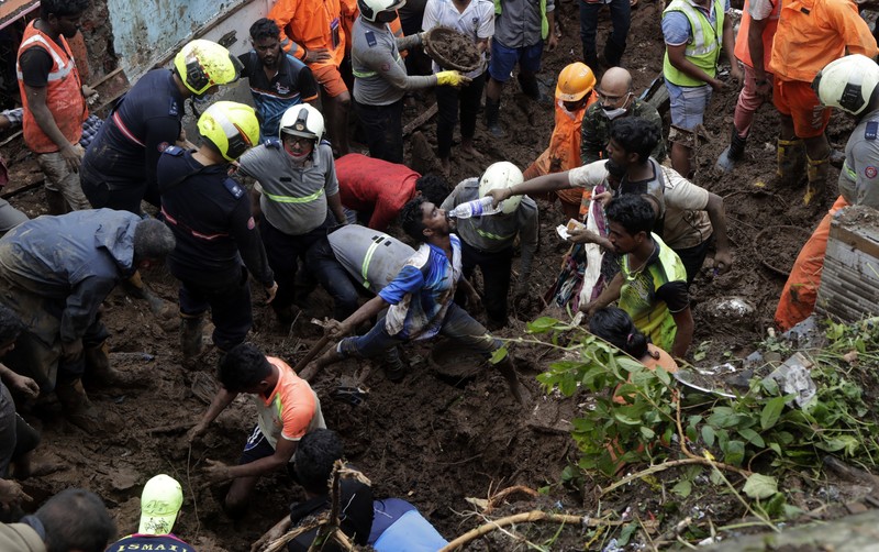 Rescuers carry a dead body of a man after a wall collapsed on several slum houses heavy monsoon rains in the Mahul area of Mumbai, India, Sunday, July 18, 2021. More than a dozen people were killed in the incident. (AP Photo/Rajanish Kakade)
