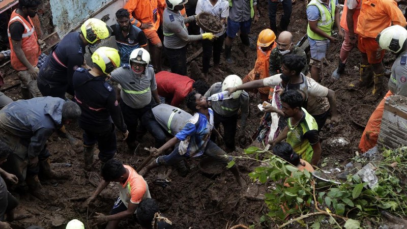 Rescuers carry a dead body of a man after a wall collapsed on several slum houses heavy monsoon rains in the Mahul area of Mumbai, India, Sunday, July 18, 2021. More than a dozen people were killed in the incident. (AP Photo/Rajanish Kakade)